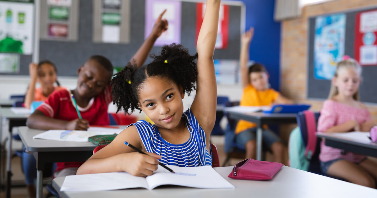 students inside the classroom raising hands